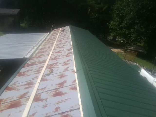 Old rusted panels beside newly installed green metal roofing — Wind Damage Roof Repair by Roofing Brothers in Weidman