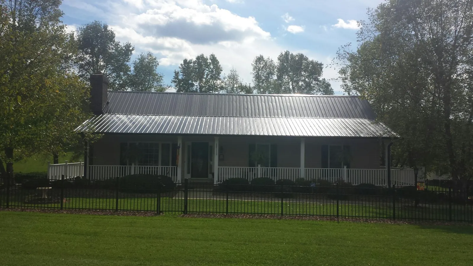 Gray metal roof on a brick ranch with a full width front porch — Gutter Guard Installation work by our crew in Weidman