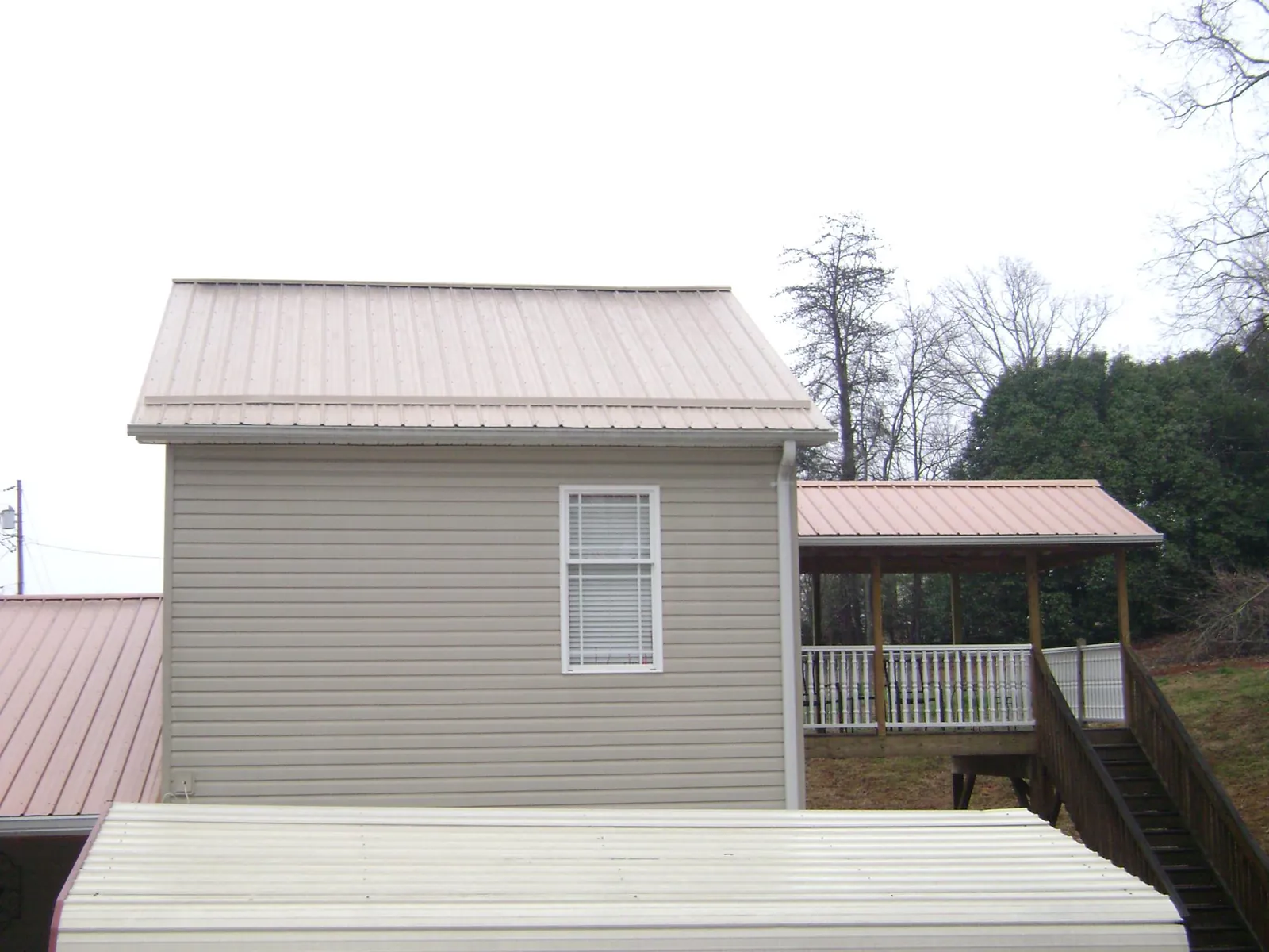 Tan metal roofs on a two story addition and attached porch, from a Roof Replacement job in Weidman