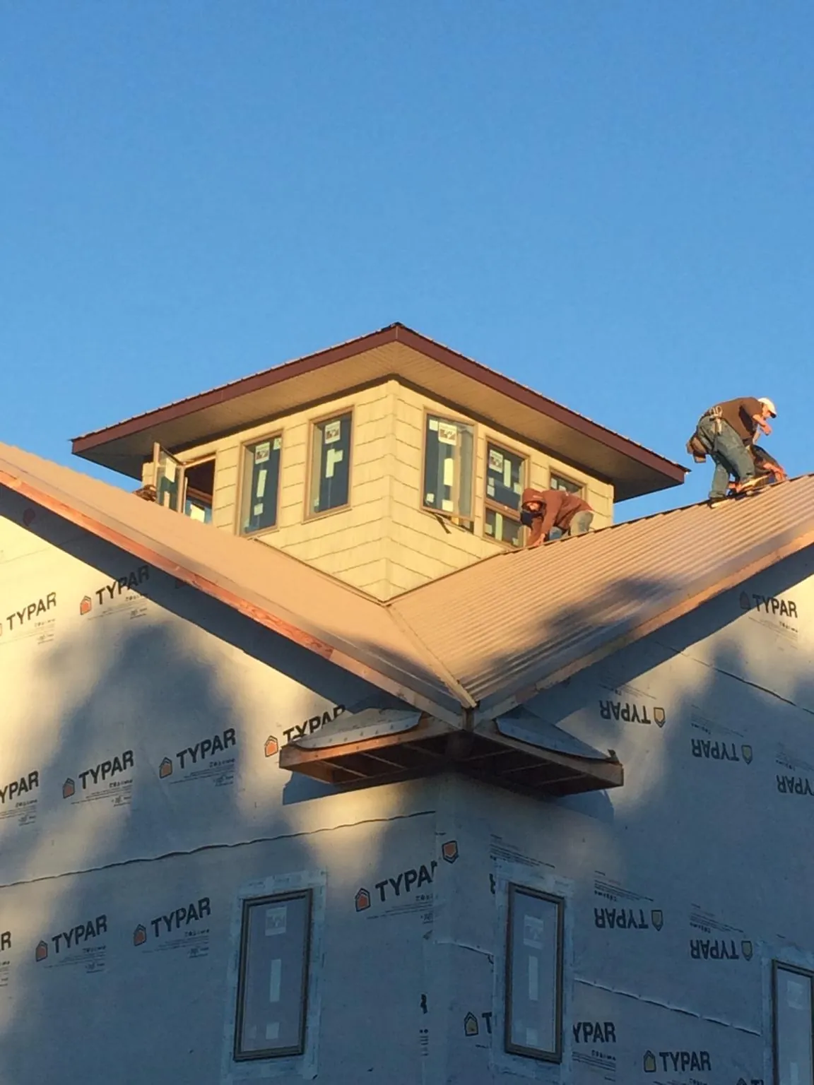 Roofers working around a rooftop cupola on a new metal roof at sunset — Roof Waterproofing in Weidman by Roofing Brothers